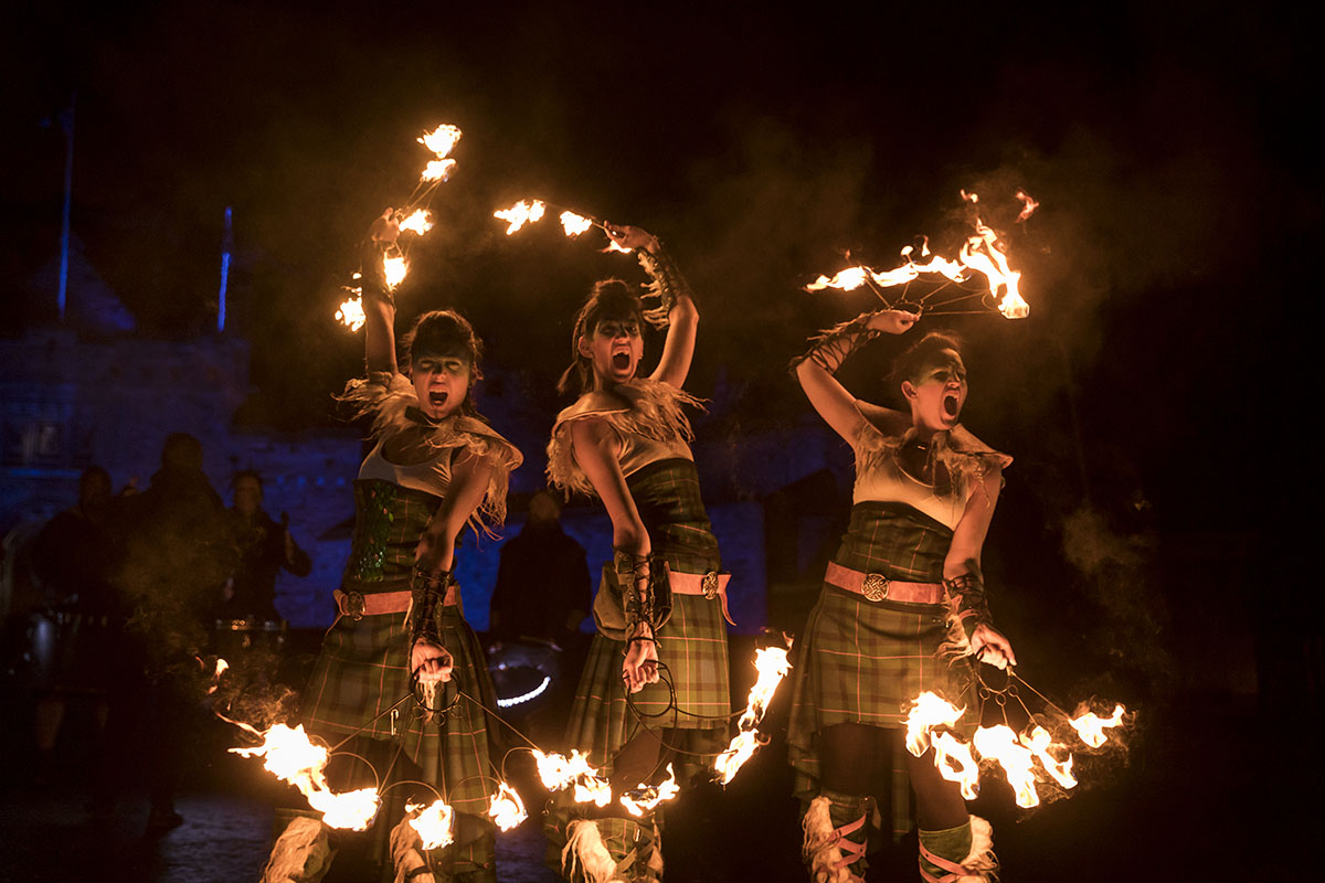 Three women in tartan dress spinning fire