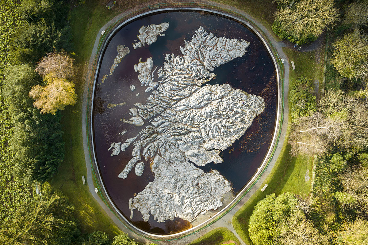 A bird's eye view of a large stone map of Scotland set into water