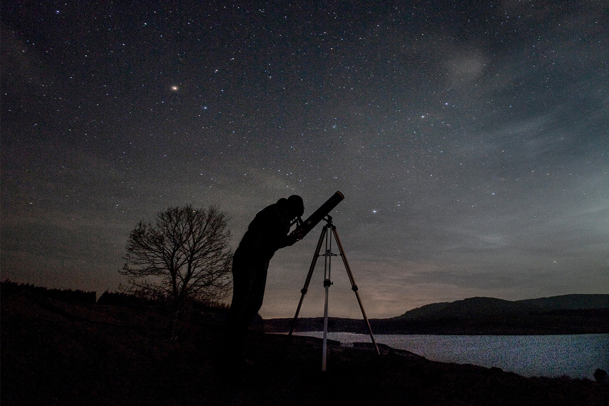 Man looking at stars at night with telescope