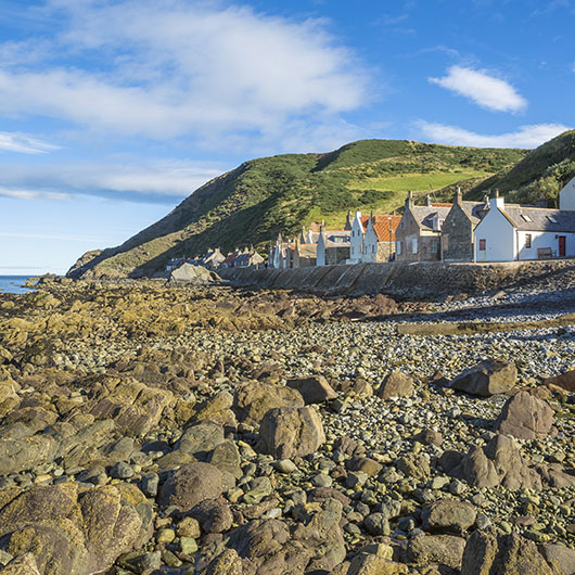 A cobbled beach with cliffside cottages
