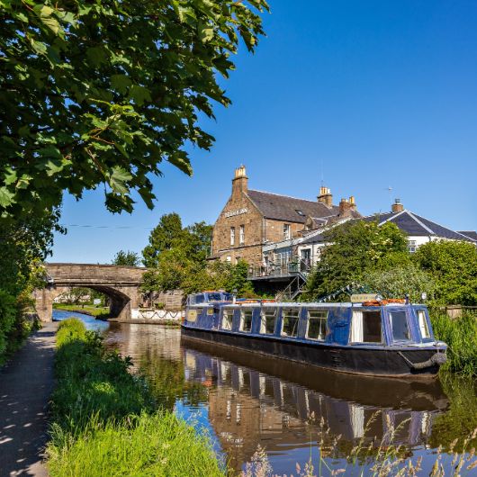 Blue boat on canal with bridge and pub