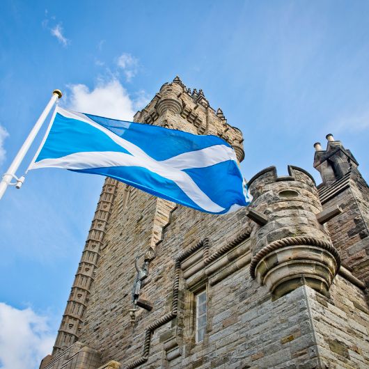 A flag flying in the wind with a castle in background