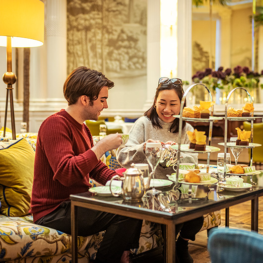 two people enjoying an afternoon tea in a grand setting