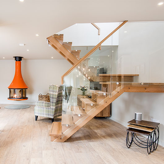 cosy open plan living with an orange suspended log burner and modern stairs.