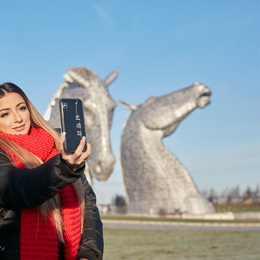 Girl taking a snap with kelpie sculptures