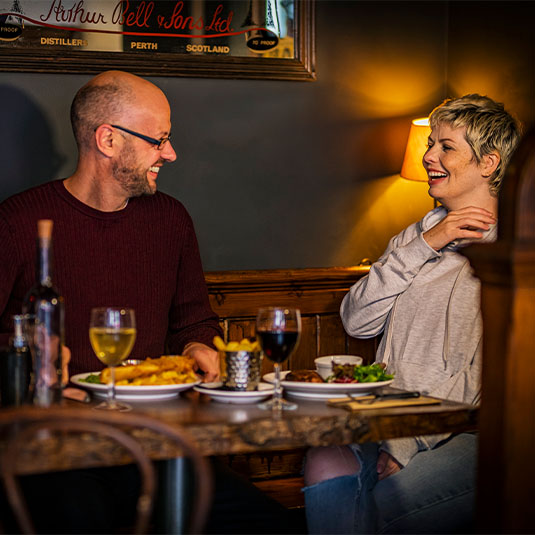 Two people enjoying food in a pub setting